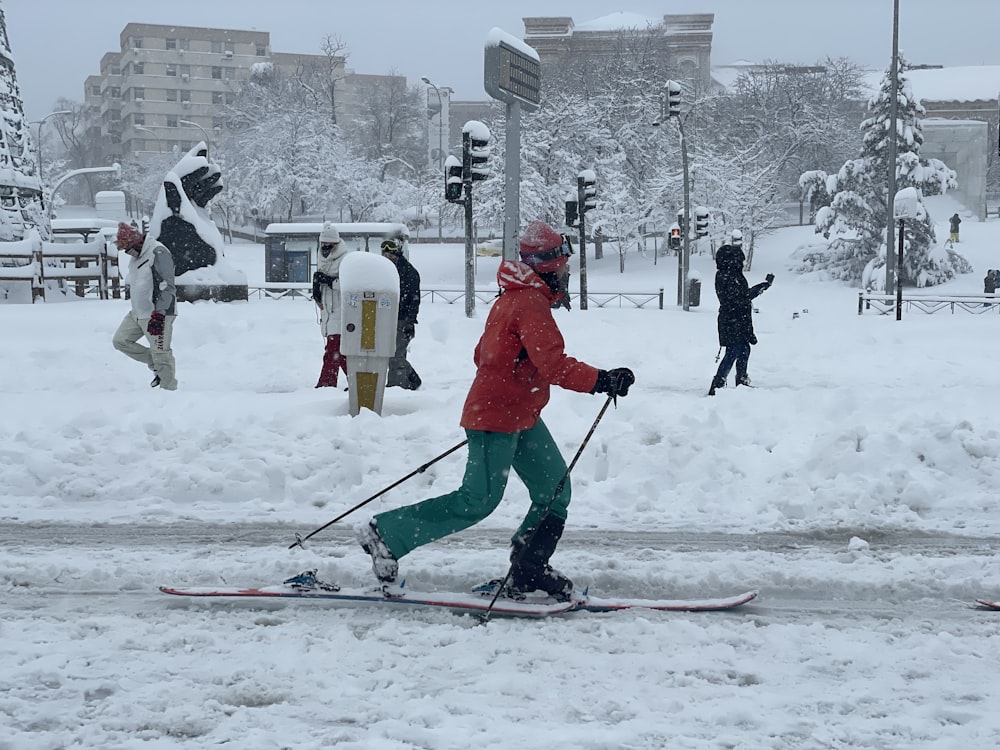 people in red jacket and pants playing ski on snow covered ground during daytime