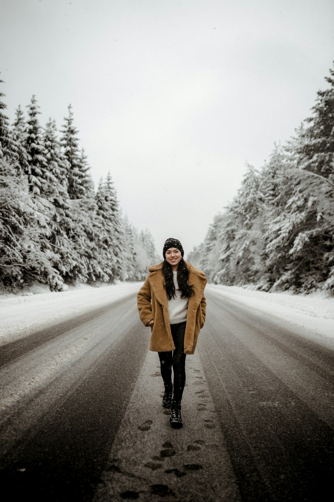 woman in brown coat standing on road covered with snow