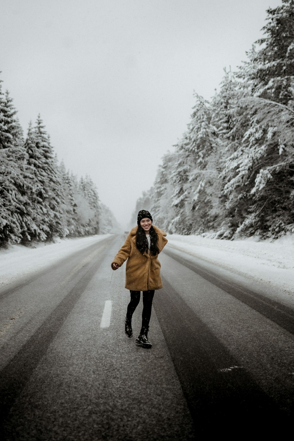 woman in brown coat standing on road during daytime