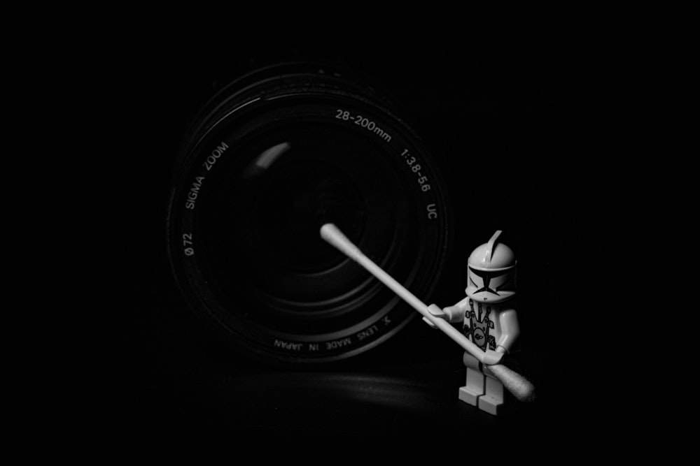 a lego figurine holding a white stick in front of a camera