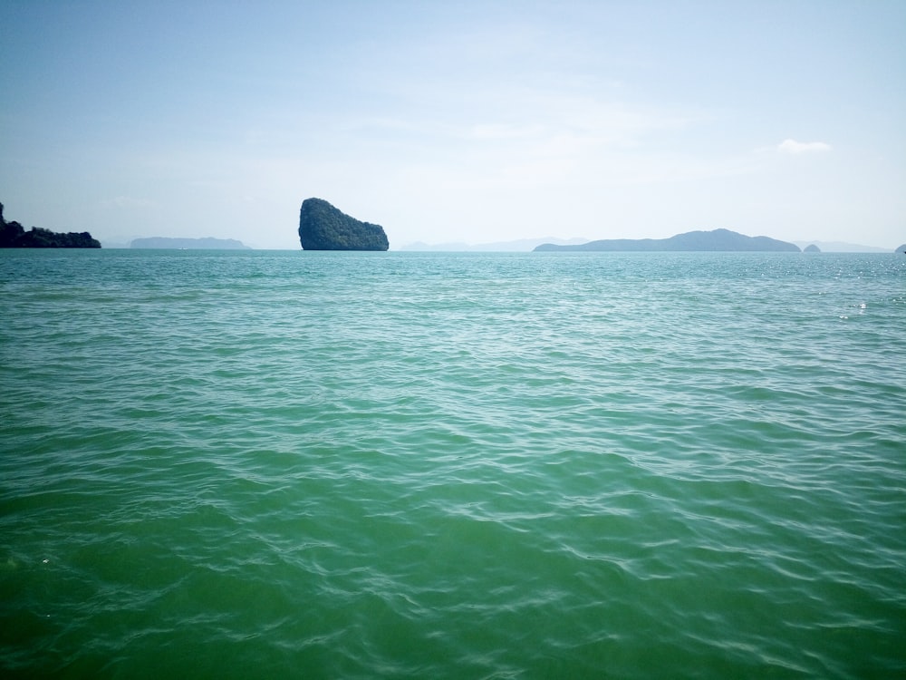 black rock formation on green sea water during daytime