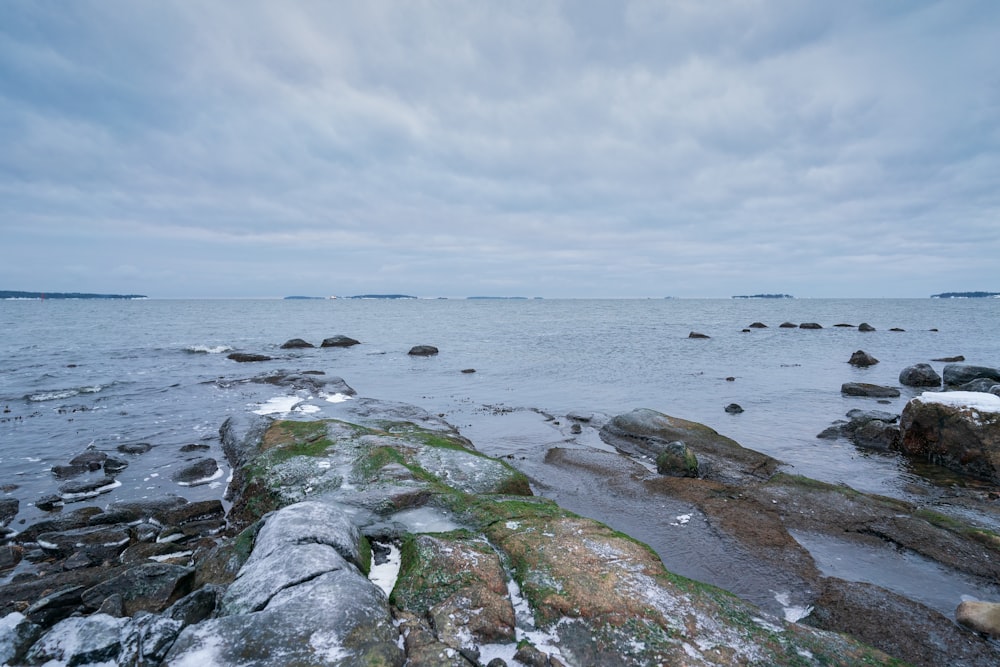 gray and green rock formation on sea under white clouds during daytime