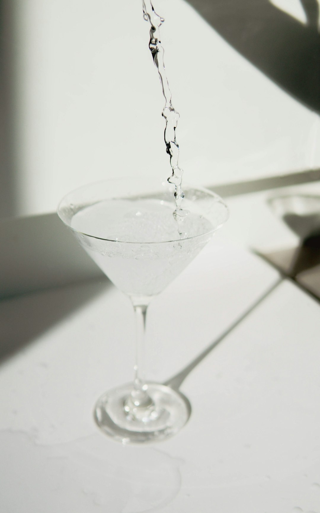 martini glass being filled with clear liquid, might be vodka