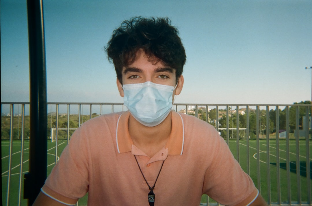 man in pink crew neck shirt with white face mask