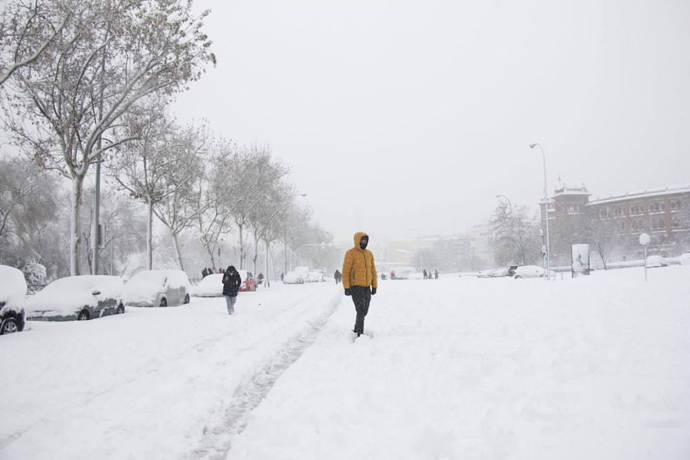 person in yellow jacket walking on snow covered ground during daytime