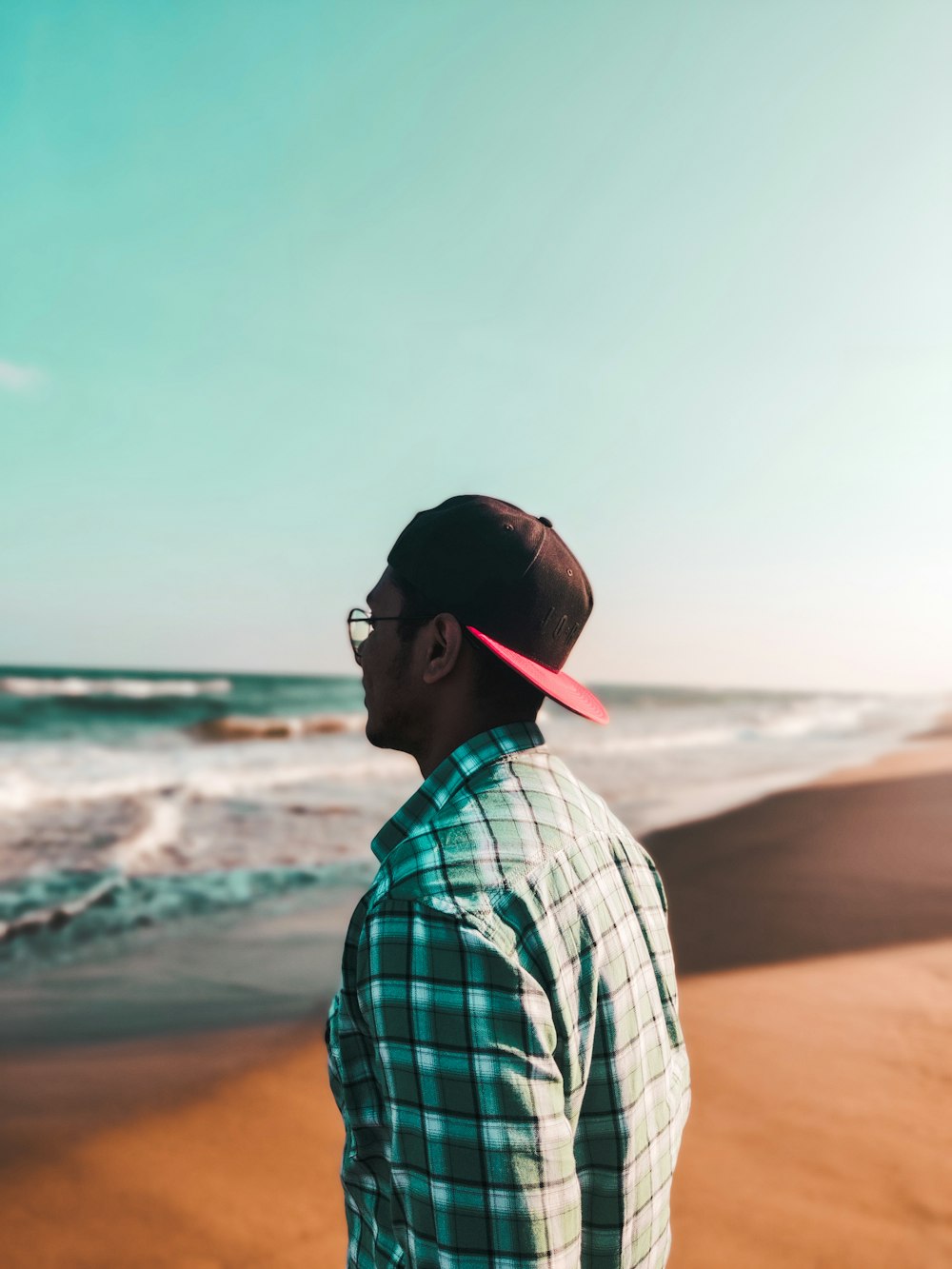 man in white and blue plaid shirt standing on beach during daytime