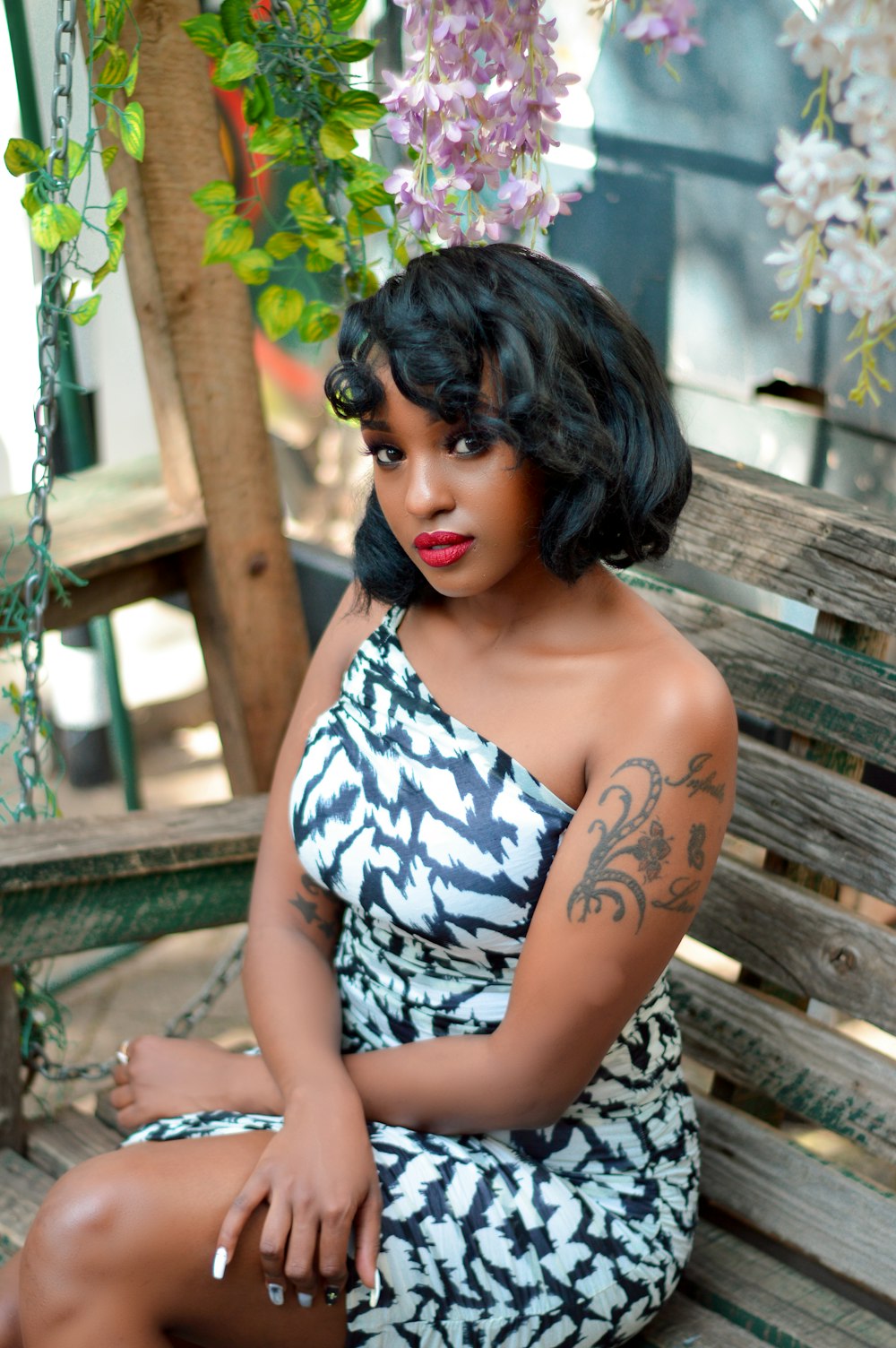 woman in white and black floral spaghetti strap top sitting on brown wooden bench