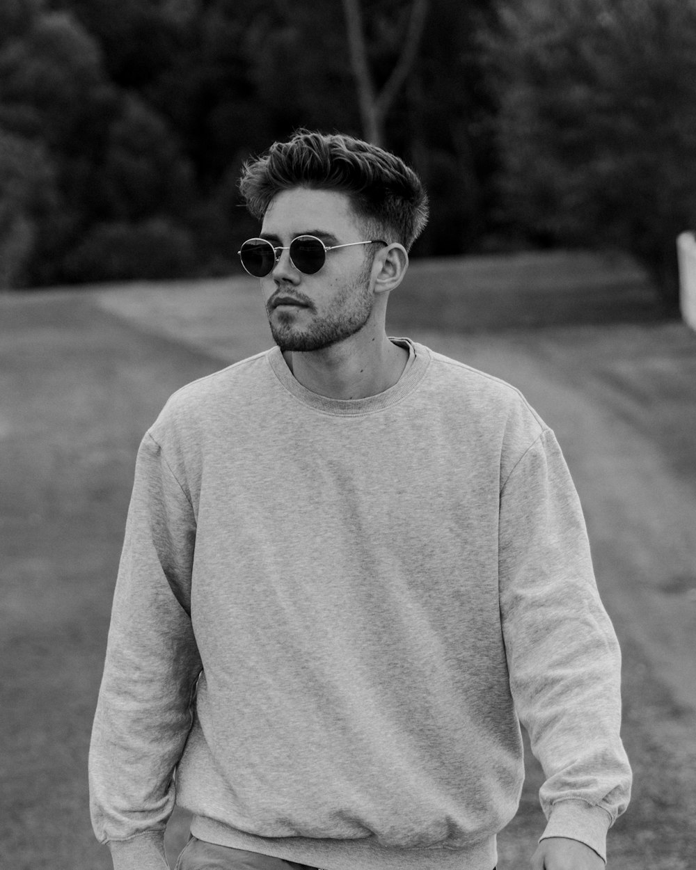 man in sweater wearing sunglasses in grayscale photography