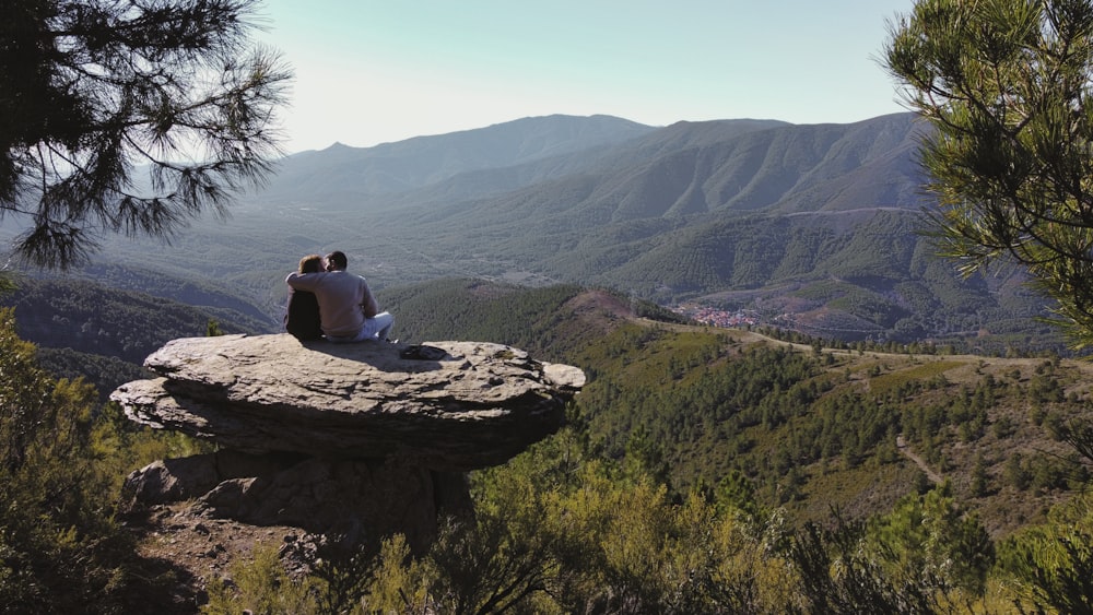 man and woman sitting on brown rock formation during daytime