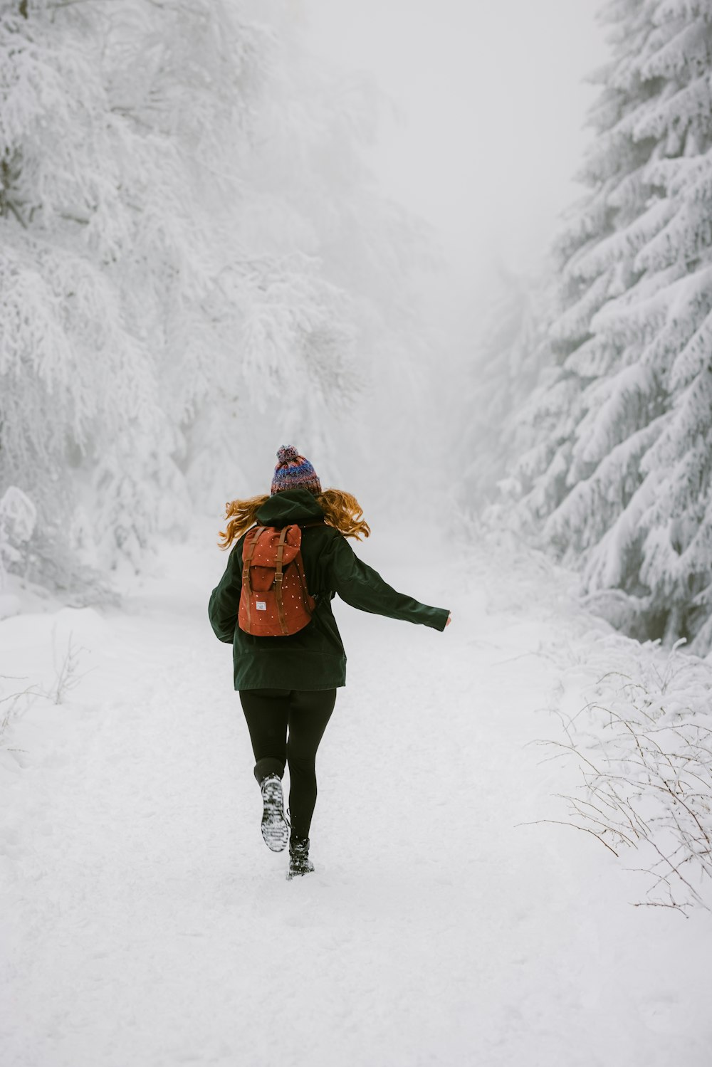 woman in brown coat standing on snow covered ground during daytime