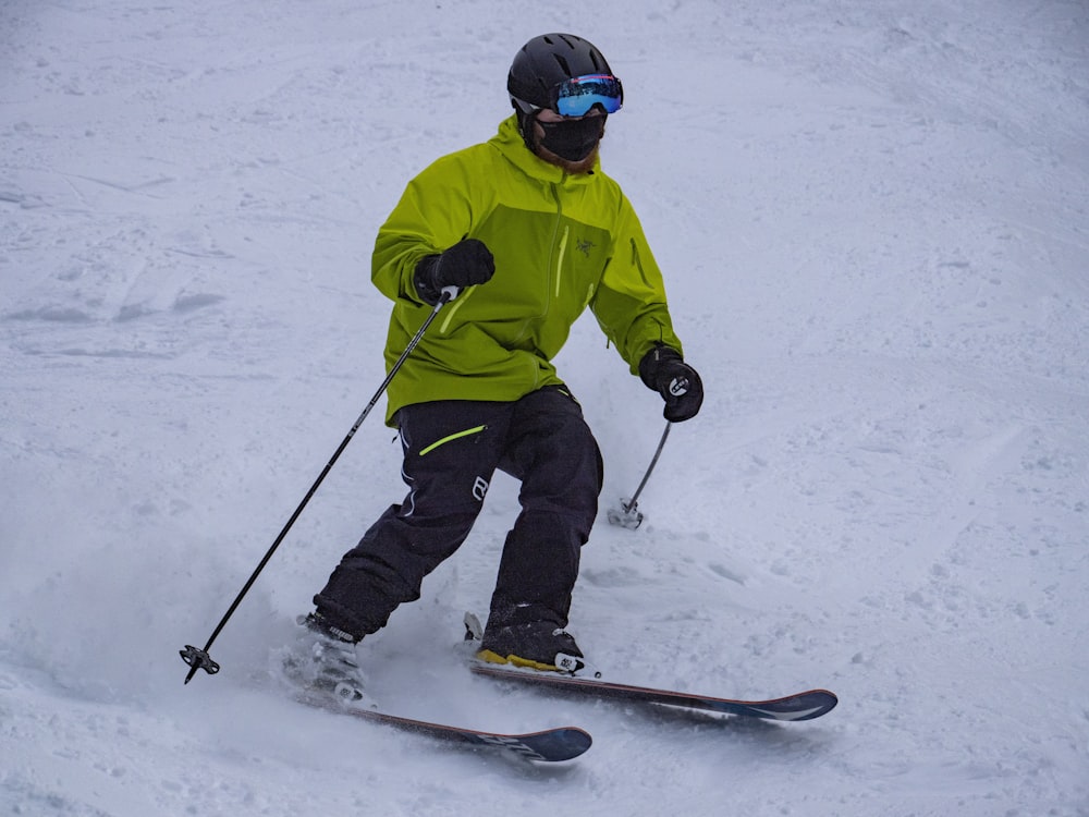 Persona con chaqueta verde y pantalones negros montando en snowboard