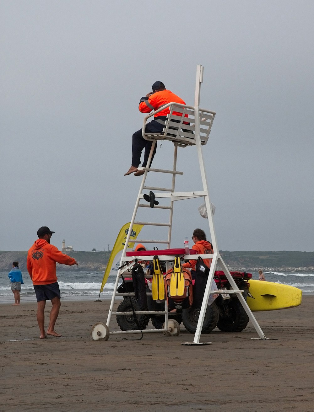 man in blue shirt and blue shorts standing on beach with yellow and red kayak