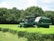A happy farmer operating a compact tractor in a lush green field.