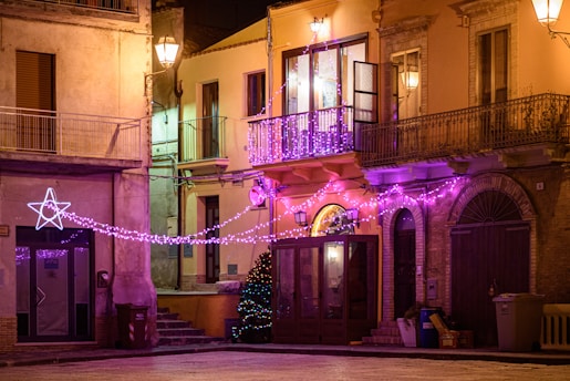 A joyful street in Villalba decorated with colorful Christmas lights at night.