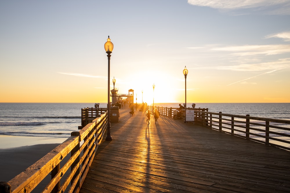 brown wooden dock on sea during sunset