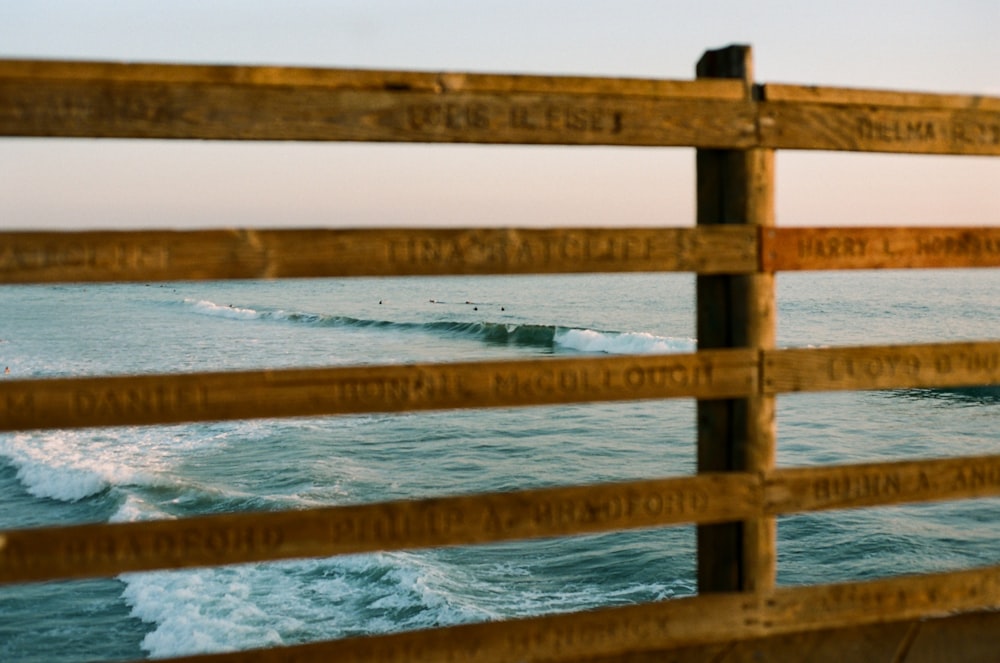 brown wooden fence on body of water during daytime