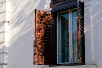 Interior shot showing a wooden window with shutters, casting soft shadows inside the room