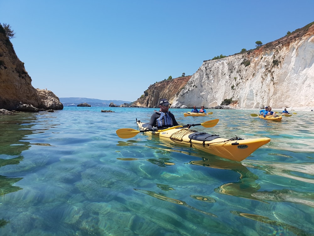 man in yellow kayak on body of water during daytime