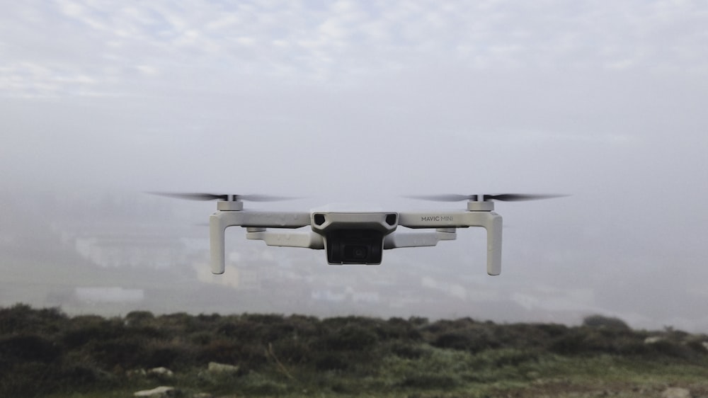 white drone flying over green grass field during daytime