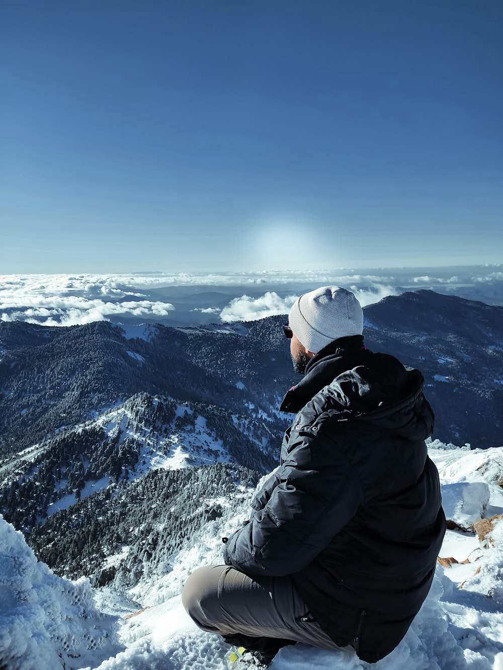 person in black jacket and white knit cap standing on snow covered mountain during daytime