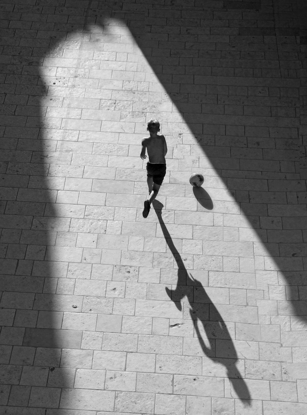 Hombre en chaqueta negra caminando sobre pared de ladrillo gris