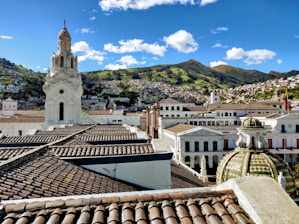 white and brown concrete building near green mountain under blue sky during daytime