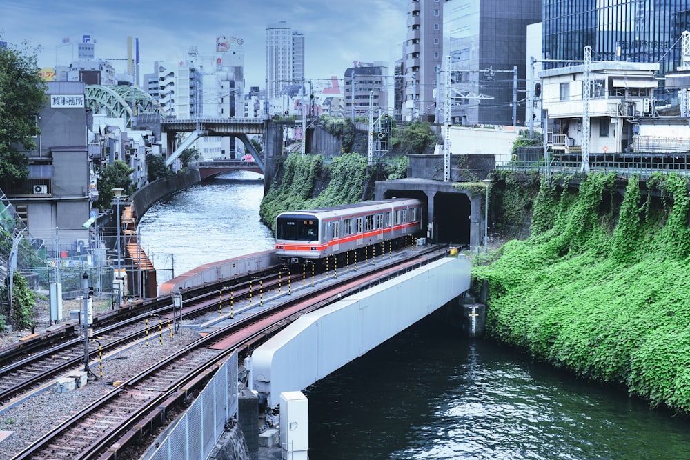 Train rouge et blanc sur rail près des bâtiments de la ville pendant la journée
