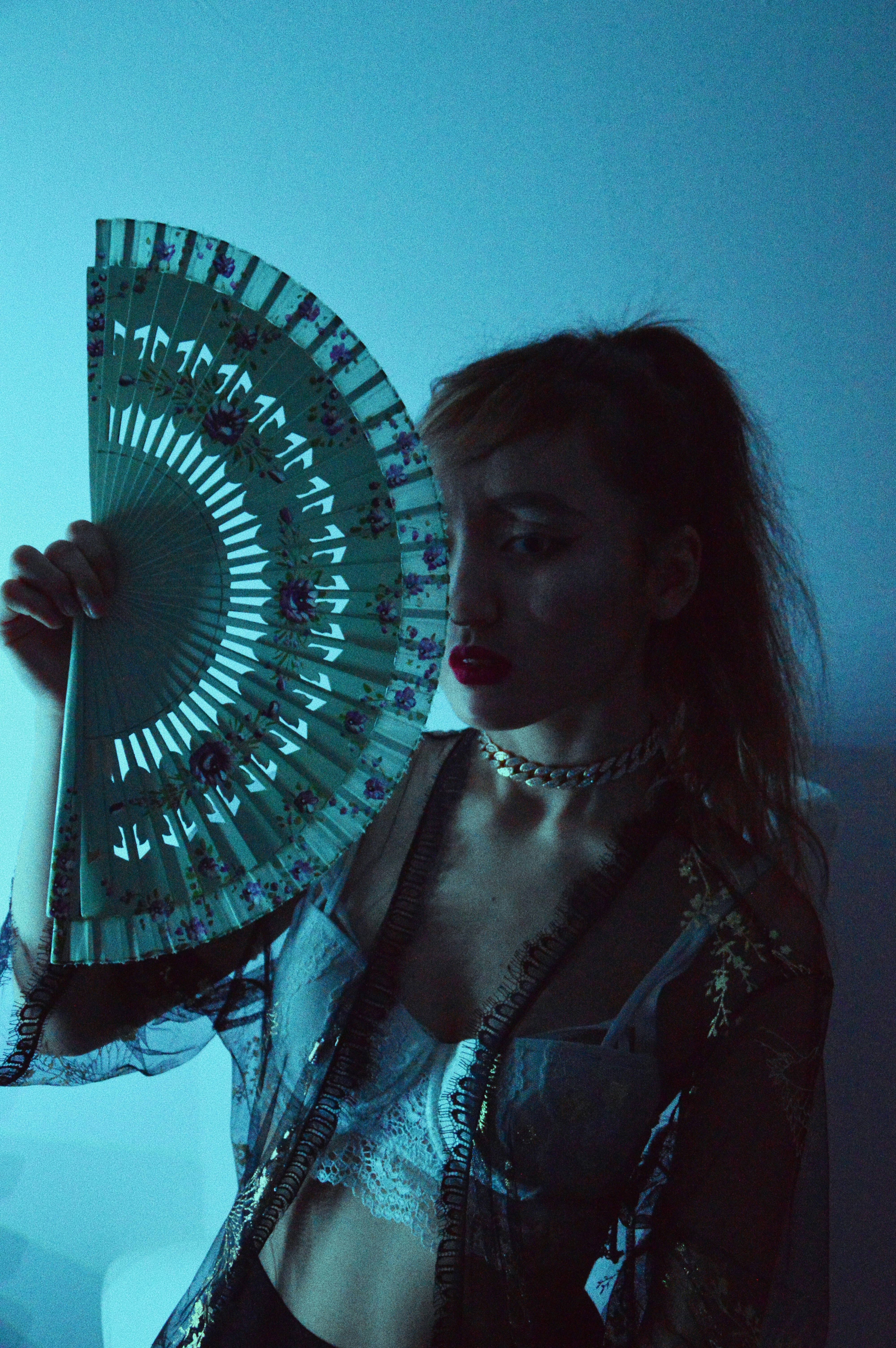 woman in black and white floral dress holding blue and white hand fan