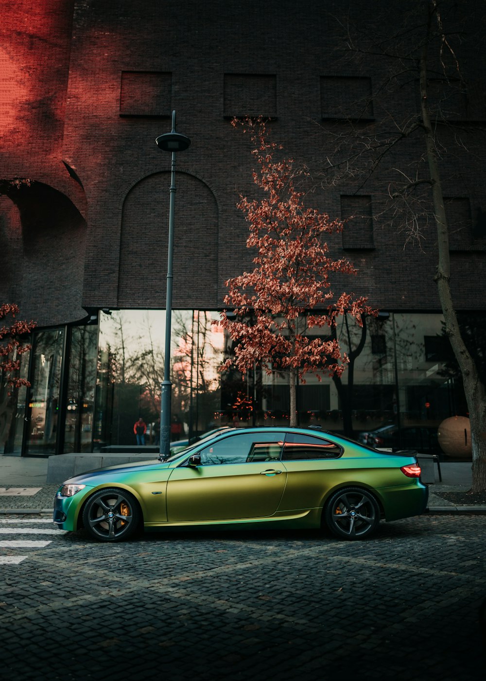 Coupé verde estacionado junto a un edificio de ladrillo marrón durante el día