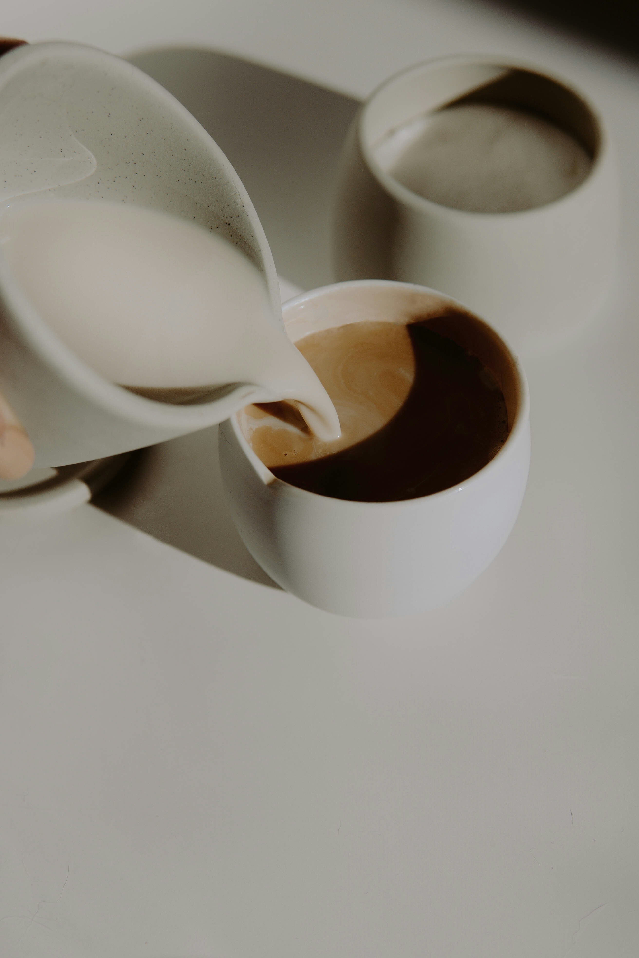 white ceramic teapot pouring brown liquid on white ceramic teacup