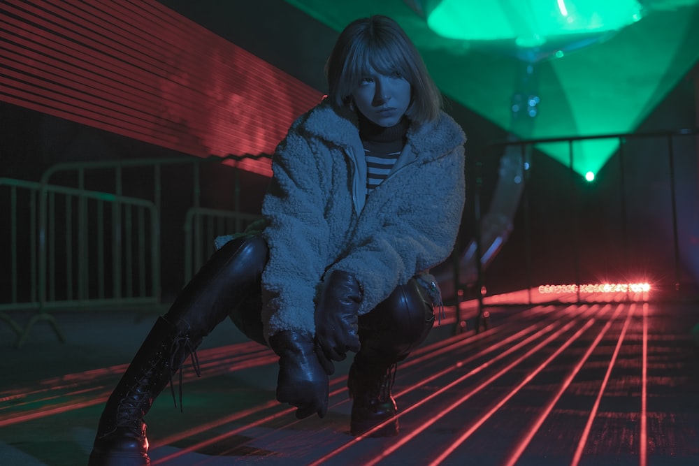 woman in black leather jacket and black pants sitting on red and white floor