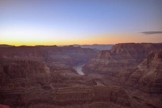 Sunrise casting golden light over the Yellowstone Grand Canyon rim with colorful rock layers.