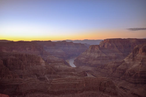 Sunrise casting golden light over the Yellowstone Grand Canyon rim with colorful rock layers.