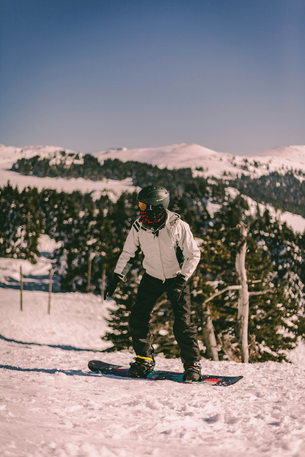 person in white jacket and black pants standing on snow covered ground during daytime