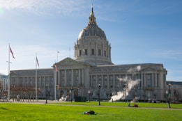 white concrete building with green grass field and people walking around during daytime