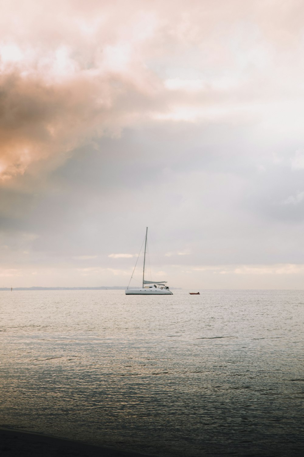 white sailboat on sea under cloudy sky during daytime
