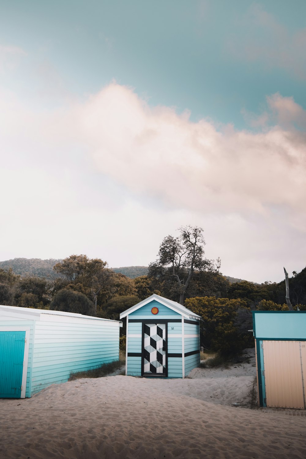 white and blue wooden house near green trees under white clouds during daytime