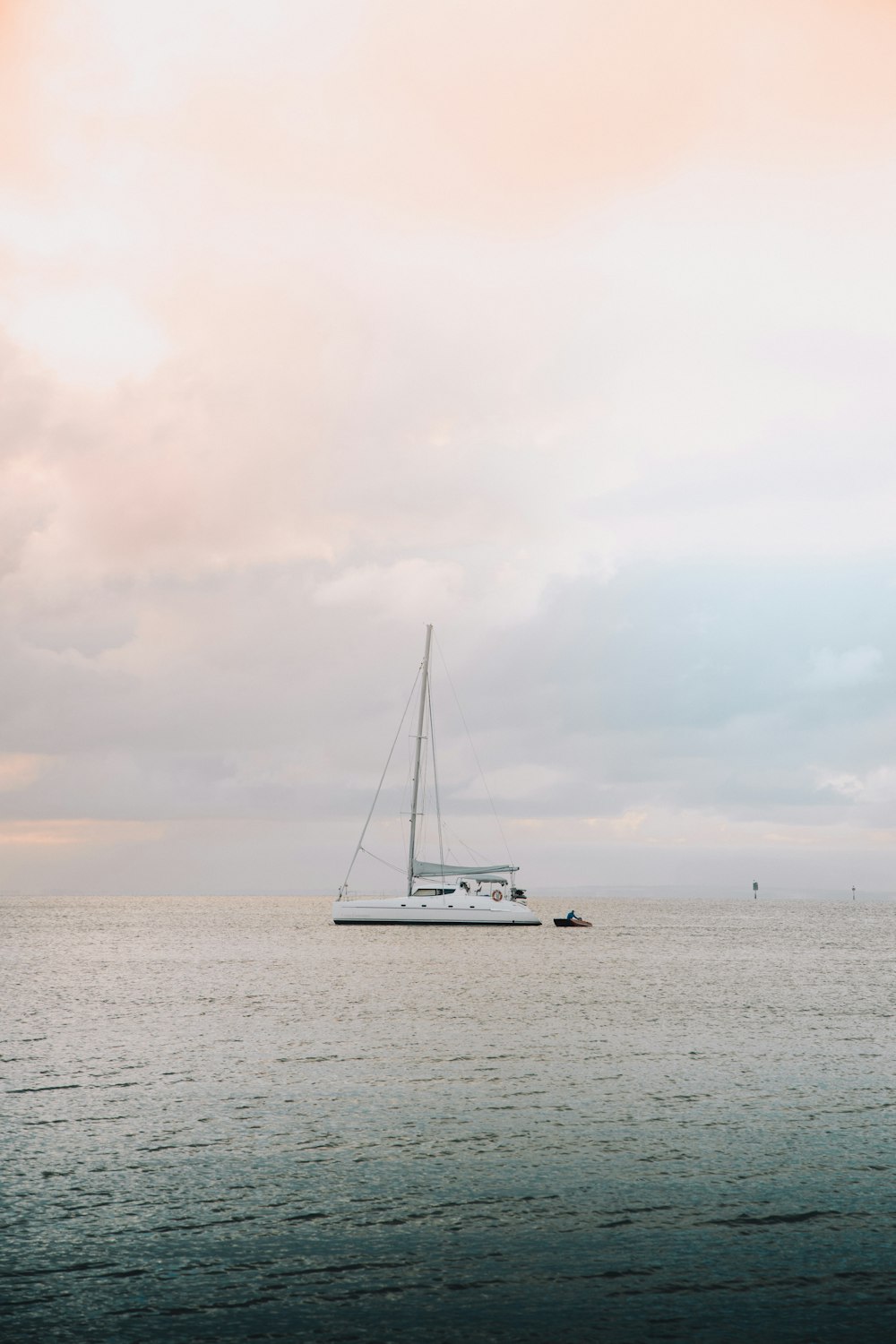 white sailboat on sea under white clouds during daytime