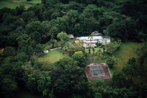 A wide aerial view capturing the sprawling 69-acre property with lush greenery and the modern ICF house at its center