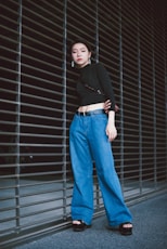 woman in black long sleeve shirt and blue denim jeans standing beside black metal roll up