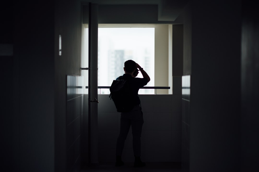 woman in black shirt standing in front of window,