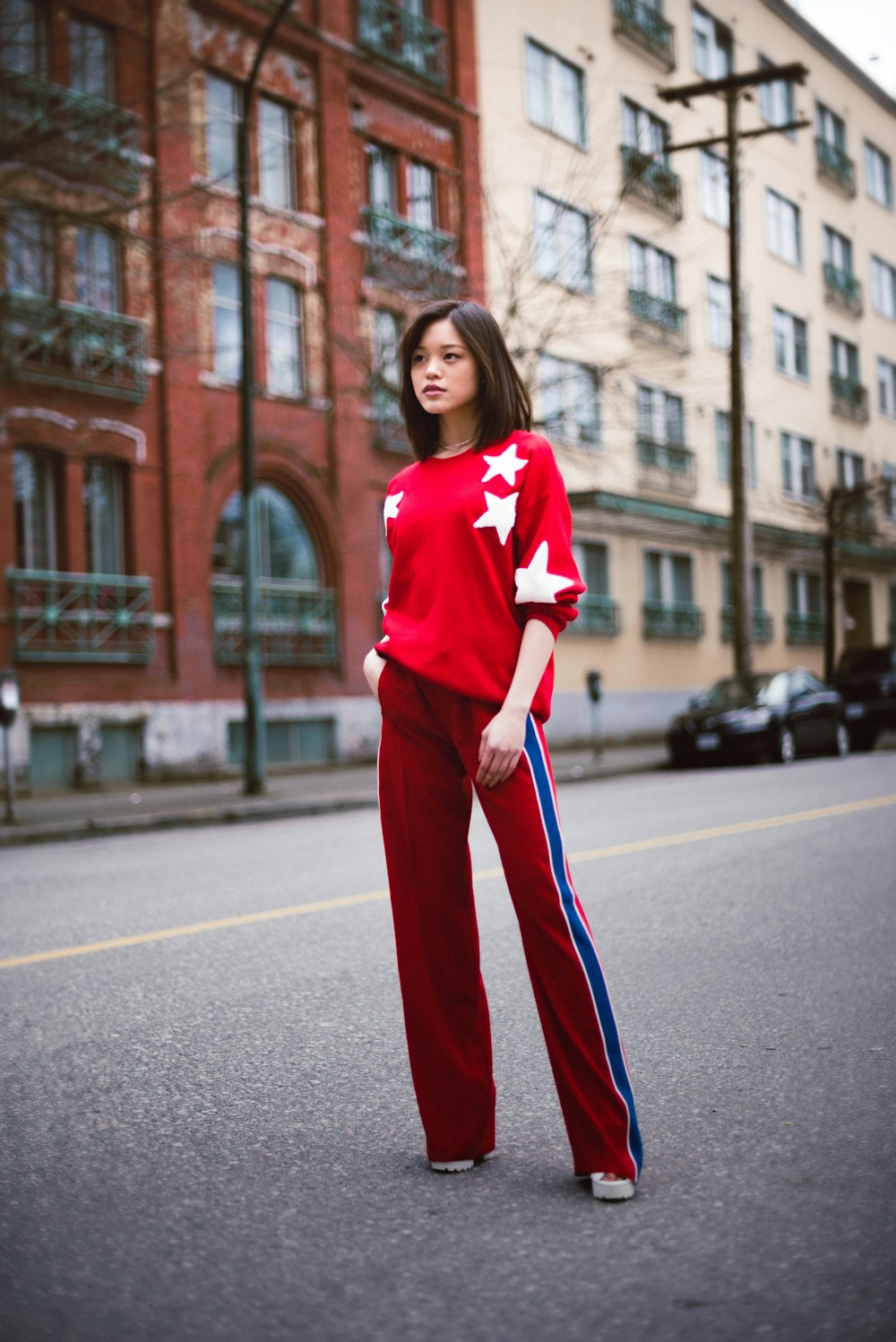 woman in red and white long sleeve shirt standing on road during daytime