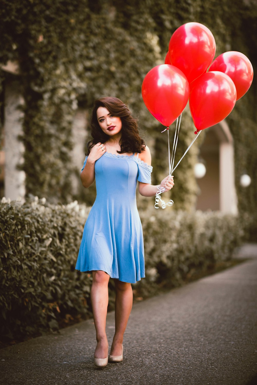 woman in blue sleeveless dress holding red balloons
