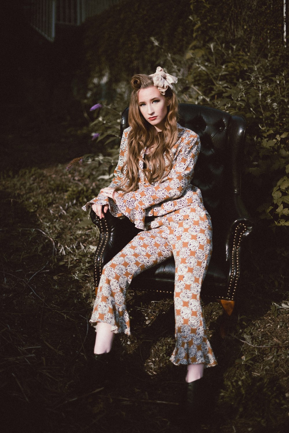 woman in brown and white floral long sleeve dress sitting on black leather armchair