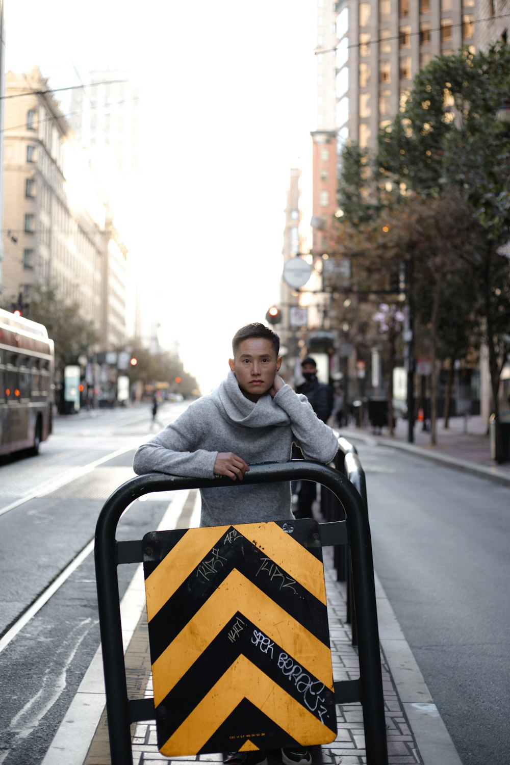 man in gray hoodie sitting on black and yellow road sign during daytime