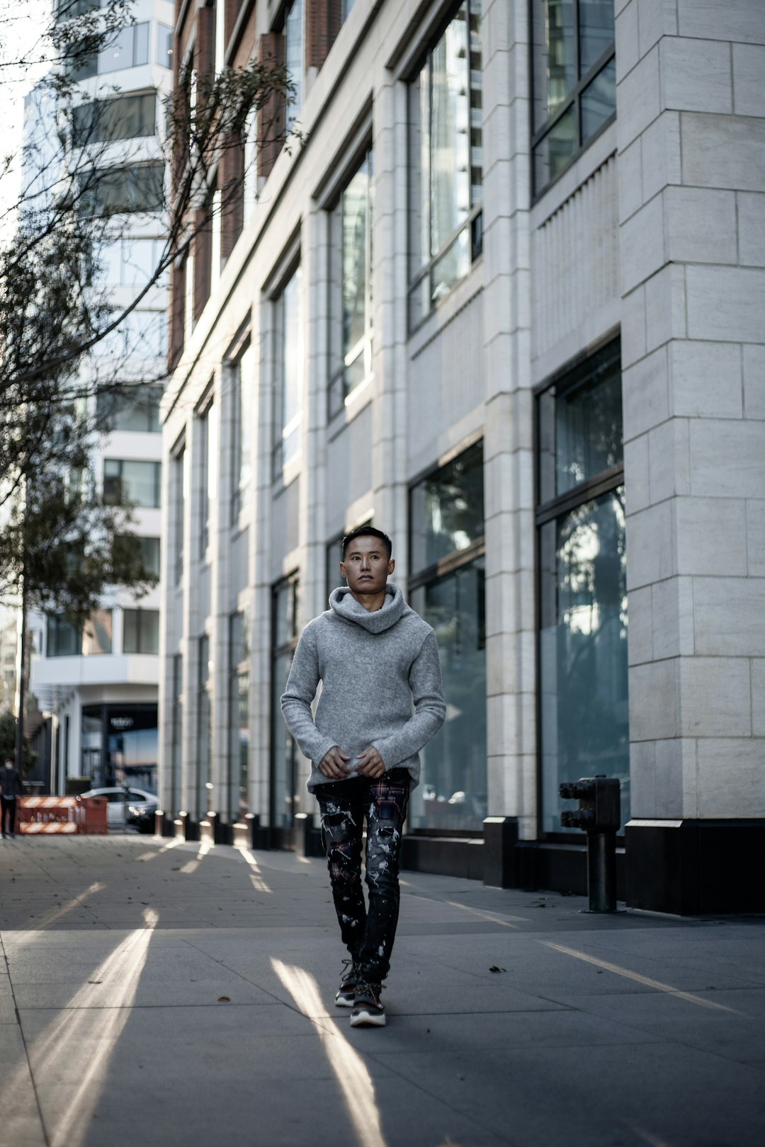 woman in gray sweater and black pants standing on sidewalk during daytime