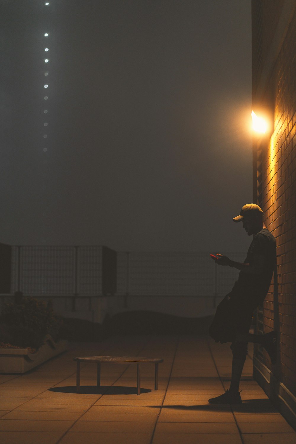 man in black jacket and hat standing on the street during night time