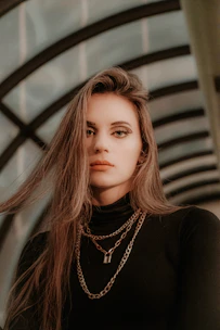 A stylish model showcasing layered contemporary necklaces in a minimalist urban setting.