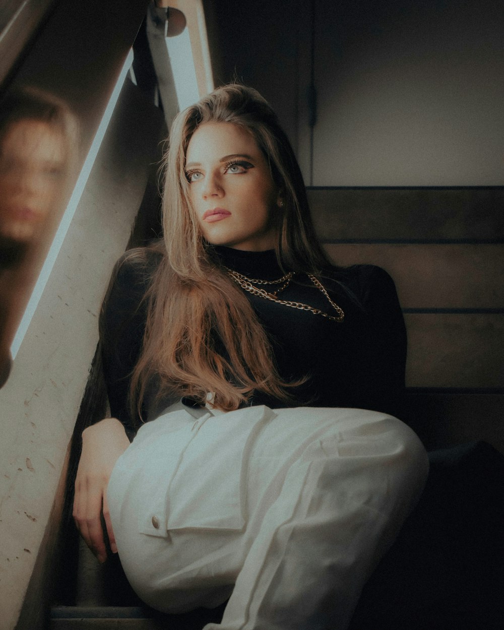 woman in white long sleeve shirt and black pants sitting on stairs