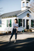 A smiling woman standing confidently in front of a community center, embodying leadership.